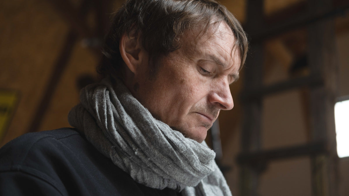 Man wearing a gray scarf in a dimly lit room
