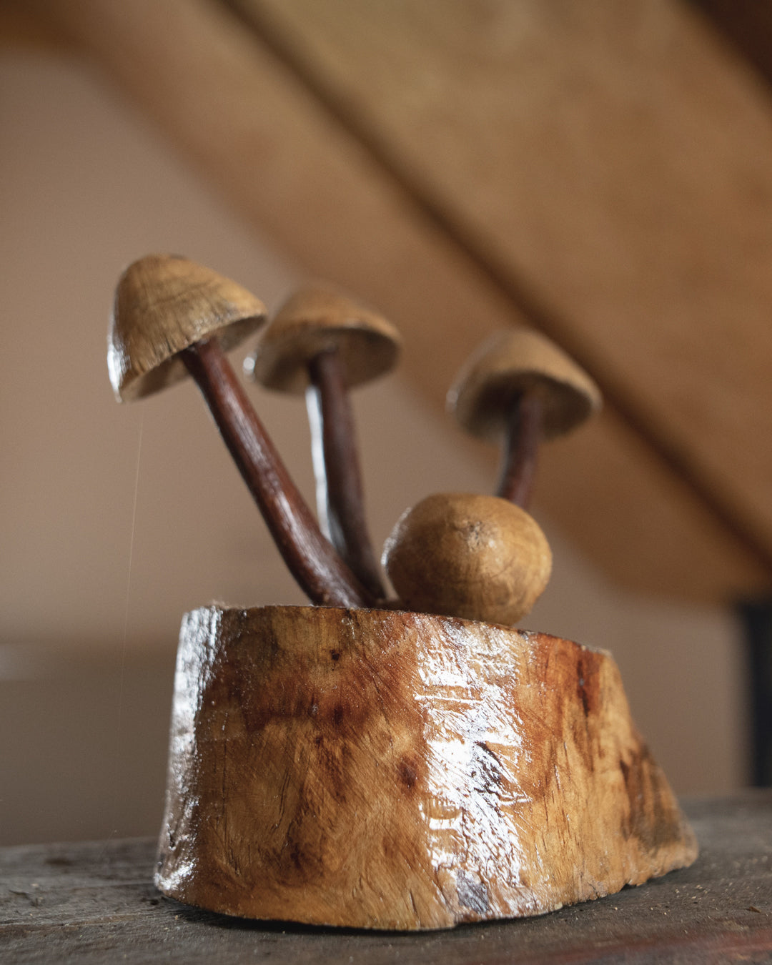 Wooden mushroom sculpture on a wooden base with a blurred background