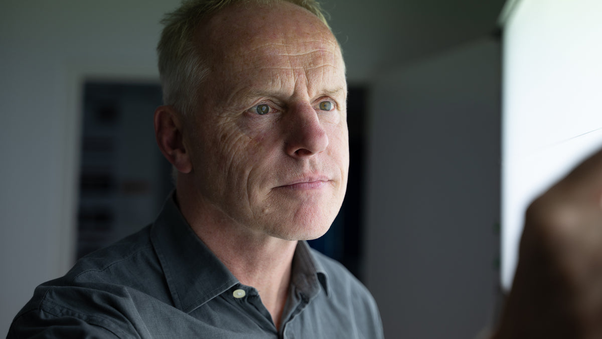 Man wearing a gray shirt in a blurred indoor setting