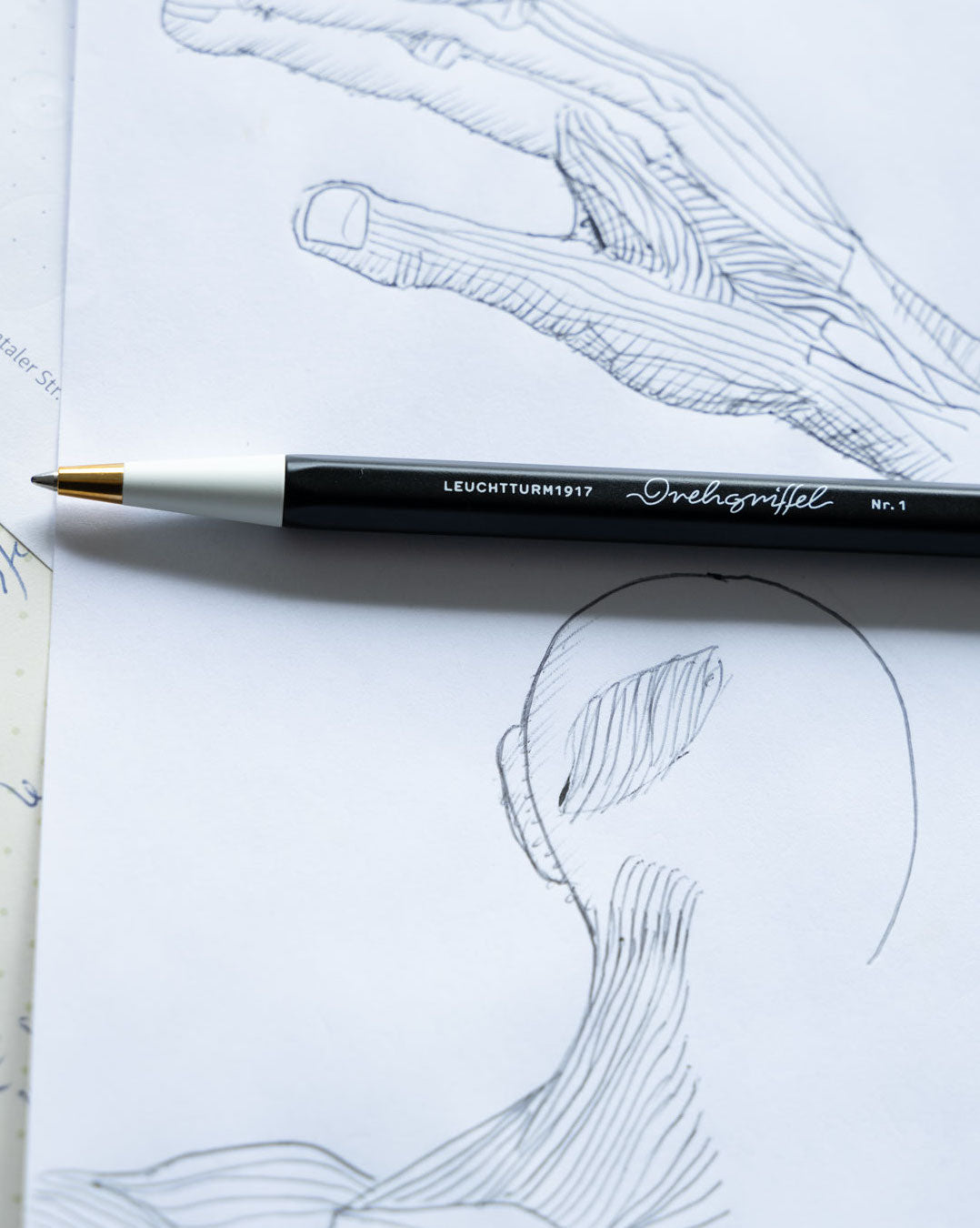 Leuchtturm1917 pen on a drawing of a hand and face with artistic lines.