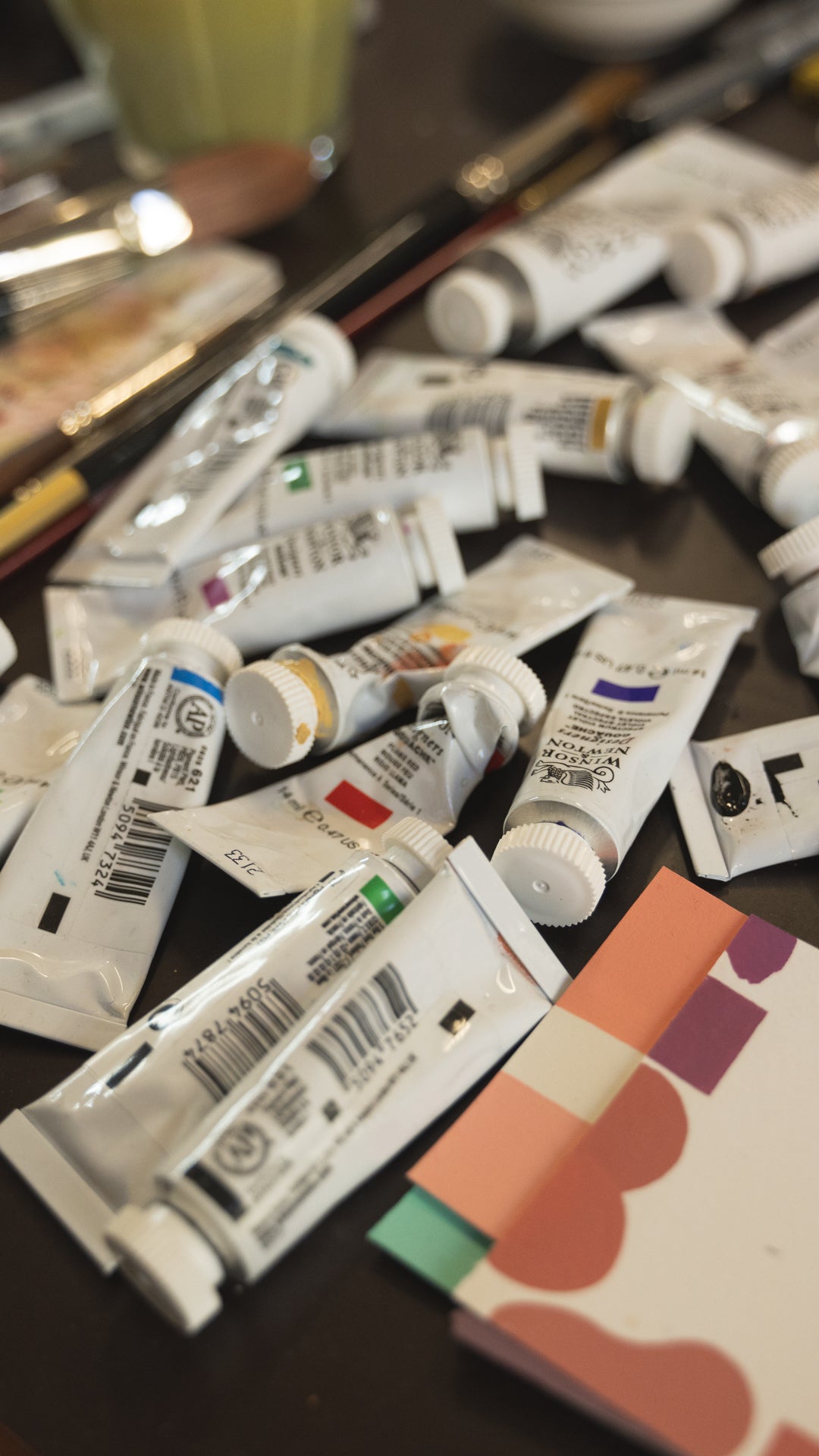 Multiple tubes of paint on a surface with a blurred background