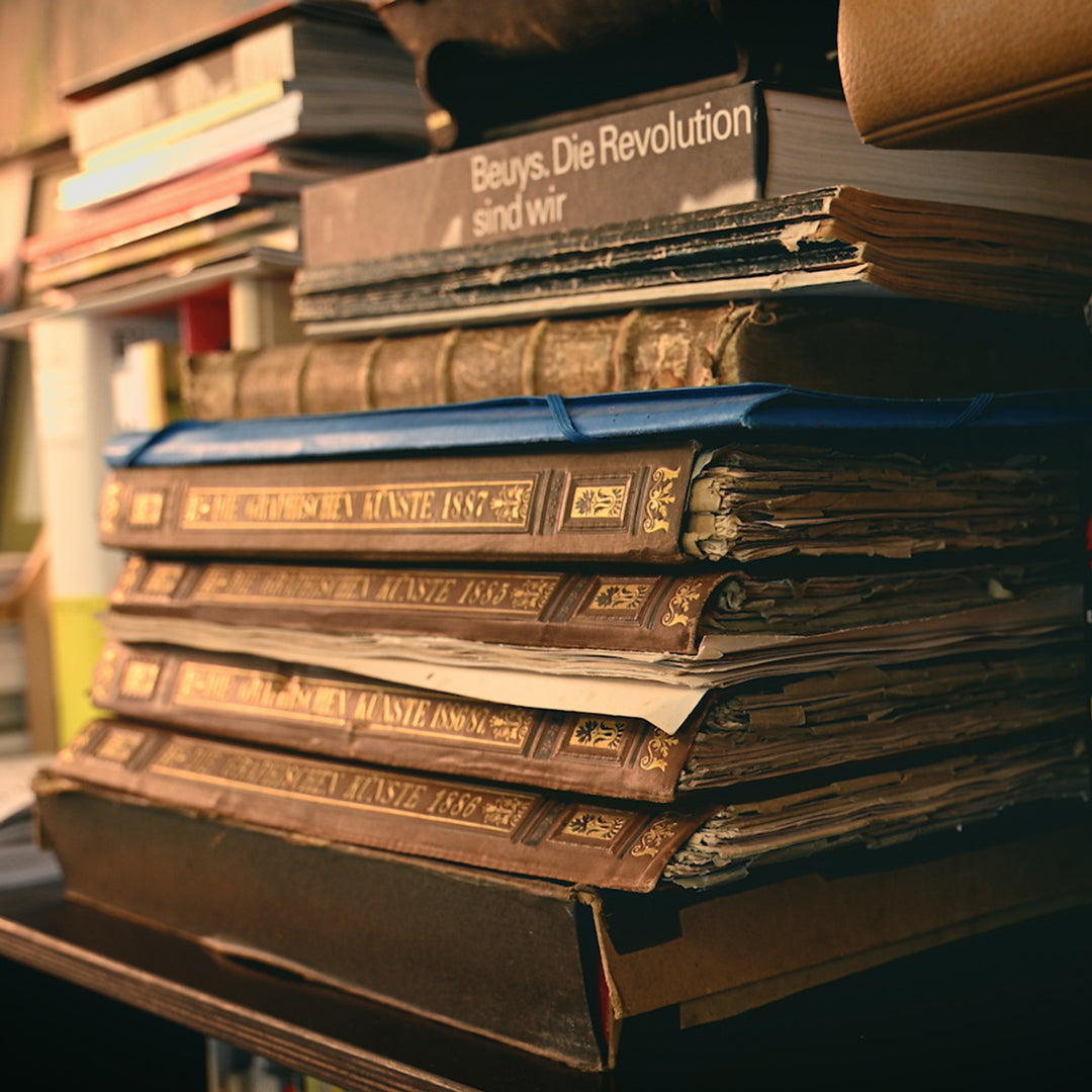 Stack of old books with visible titles on a shelf