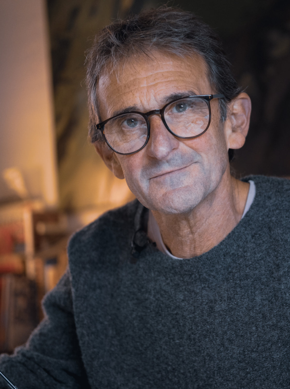 Man wearing glasses and a dark sweater in a softly lit room