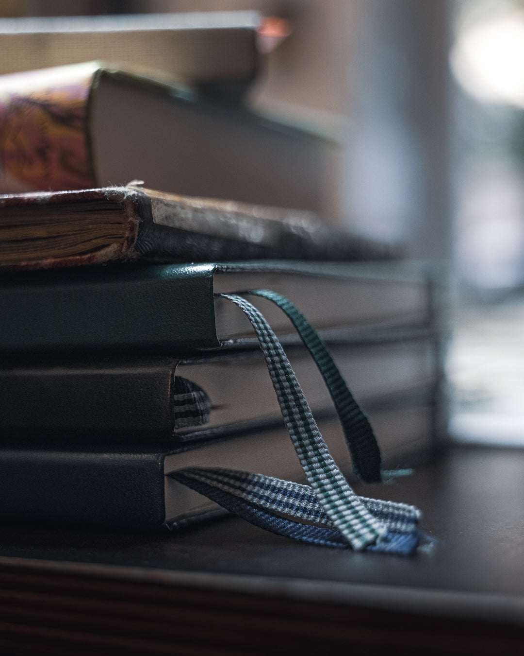 Stack of books with a ribbon marker on a wooden surface