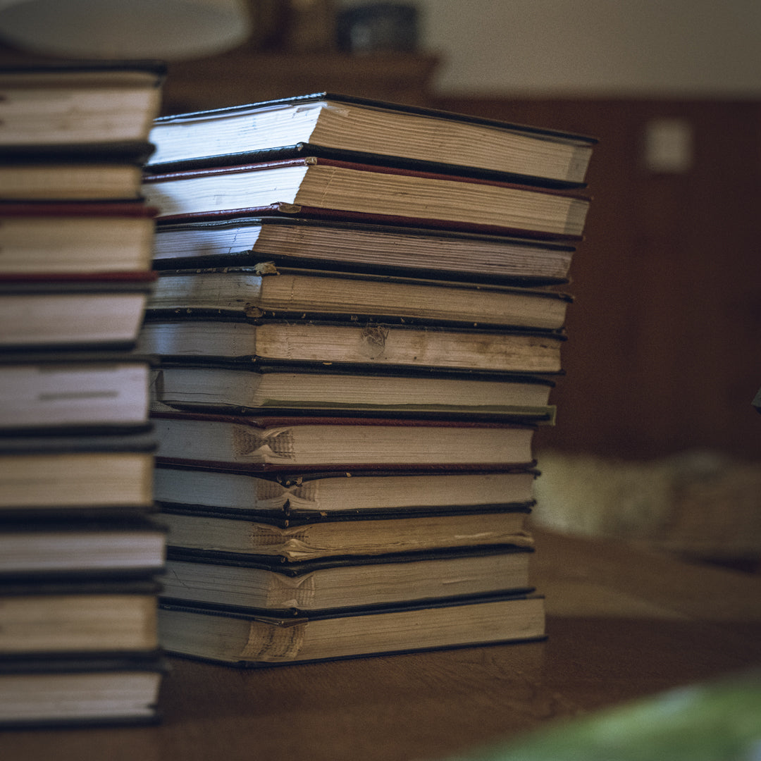 Stack of old books on a wooden surface with a blurred background