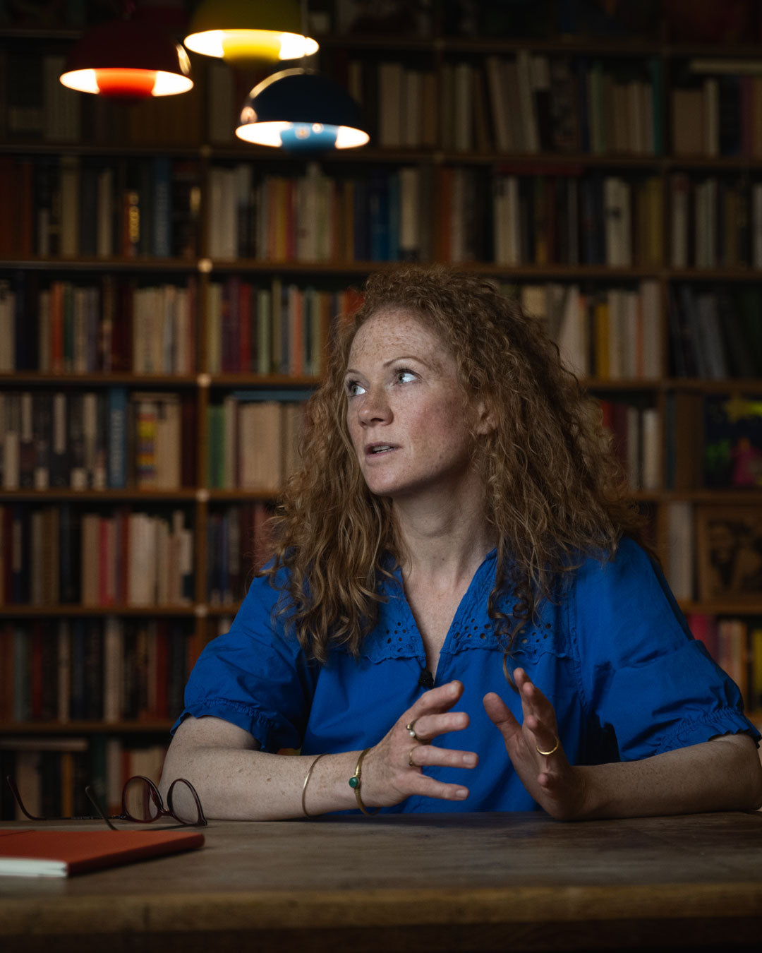 Woman in a blue shirt sitting at a table in a library setting
