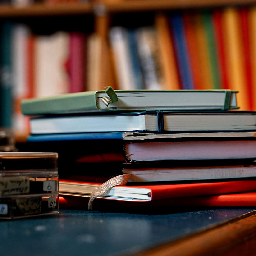 Stack of books with a blurred bookshelf in the background