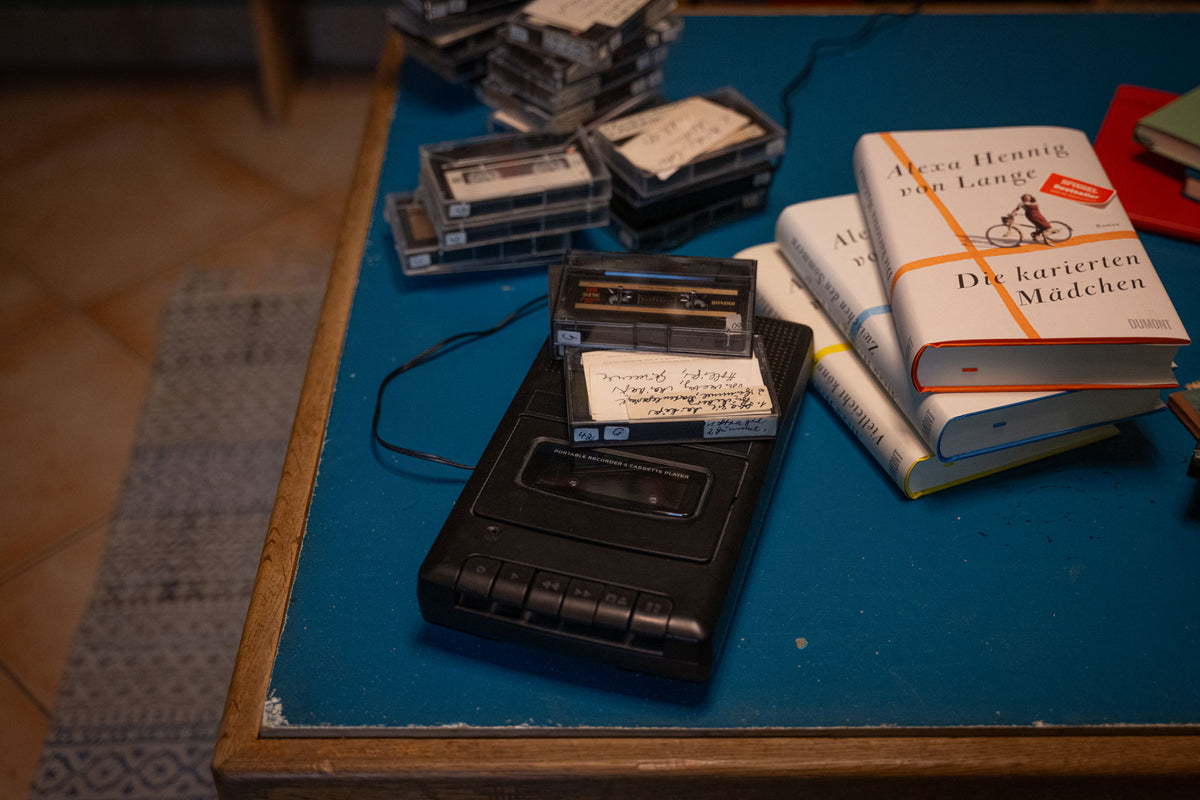Vintage cassette player and tapes on a blue table with books in the background